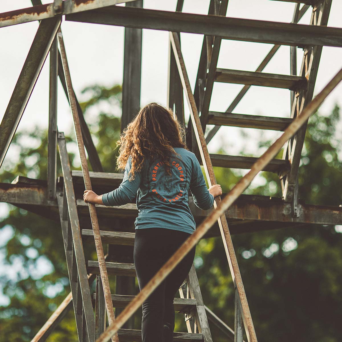Model wearing Prentice Cooper State Forest long sleeve while climbing a watch tower